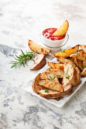 Roasted potato wedges with rosemary and tomato sauce, selective focusの写真素材