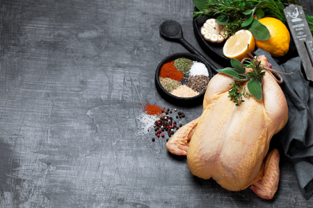 Raw whole chicken, herbs, spices and lemon, selective focus. Copy space background.の写真素材