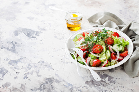 Fresh salad with cherry tomatoes, cucumbers, radishes, dill and olive oil, selective focusの写真素材
