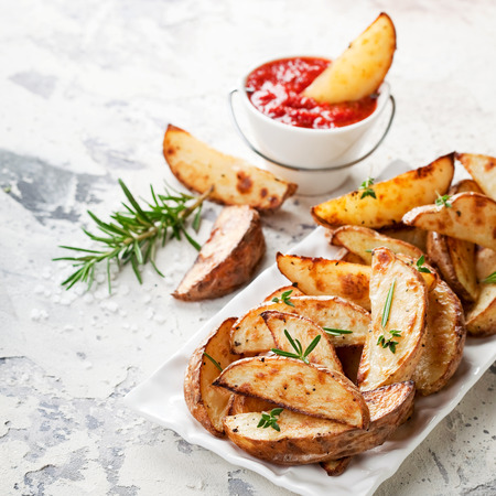 Roasted potato wedges with rosemary and tomato sauce, selective focusの写真素材