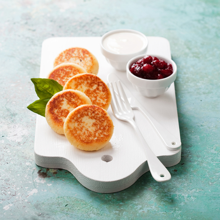 Cottage cheese pancakes Russian syrniki with cranberry jam and yogurt, selective focusの写真素材