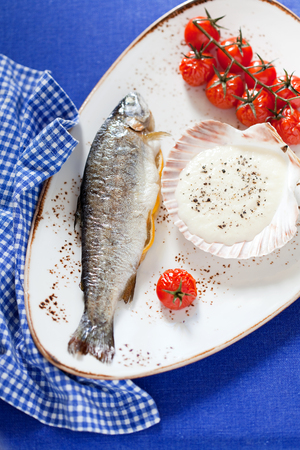 Trout baked with onion sauce and cherry tomatoes, selective focusの写真素材