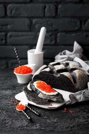 Cuttlefish ink bread and red caviar on black background, selective focusの写真素材