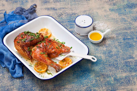 Half roasted chicken with lemon, on enameled baking dish, selective focusの写真素材
