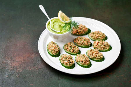 Salmon rillette with avocado on slices of cucumber, selective focusの写真素材