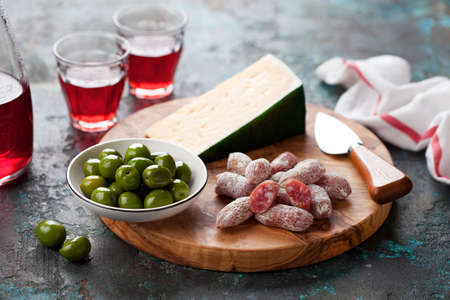 Antipasto Platter. Fuet mini sausages, green olives and cheese on wooden cutting board, selective focusの写真素材