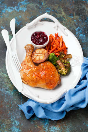 Roasted chicken leg with broccoli, fried sweet potatoes or carrots, garlic and cranberry sauce, selective focusの写真素材