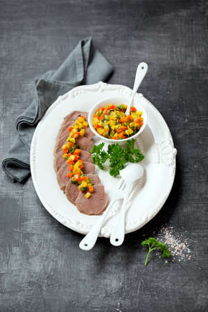 Boiled beef tongue sliced with roasted vegetables, selective focusの写真素材