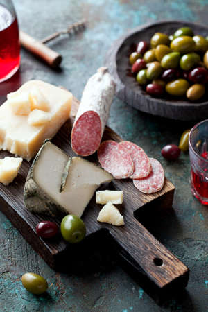 Antipasto board with sliced salami, goat cheese, assorted olives and red wine, selective focusの写真素材