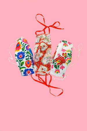 Isolated Group of Colorful, Pretty Face, Protective, Home Made Masks on a Pink Background.  A...