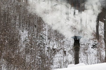 smoke from the chimney on the roof of the forest in the backgroundの写真素材