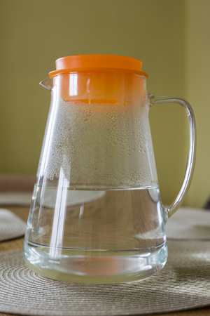 Glass jar with water and orange plastic cap.の写真素材