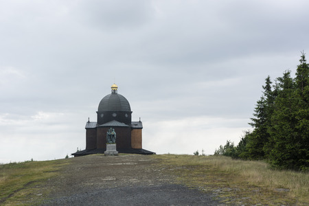 Statue of Cyril and Methodius with a chapel in the background on a hill in the mountains.の写真素材