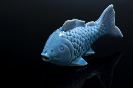 Blue ceramic small fish with black background.の写真素材