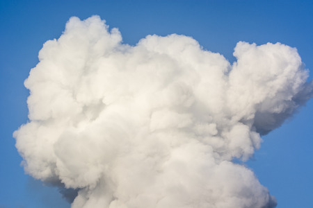 Big cloud of white smoke on a blue sky.