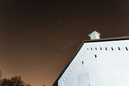 Night sky with stars and building with chimney on the edge.の写真素材