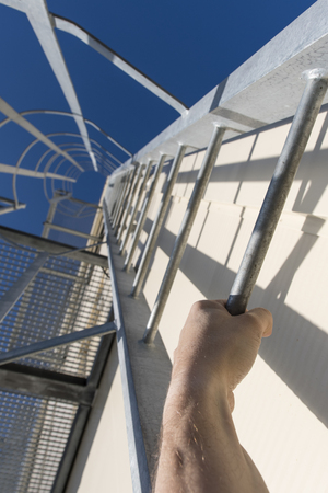 Metal ladder with holding hand and grate floor on outer building structure.の写真素材
