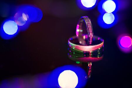 Wedding rings of white gold on a black shiny background.の写真素材