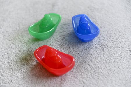 Three small colored plastic pumps on a gray carpet.