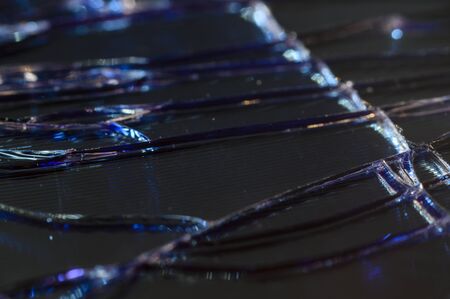 Cracks on the glass of a mobile phone in detail.