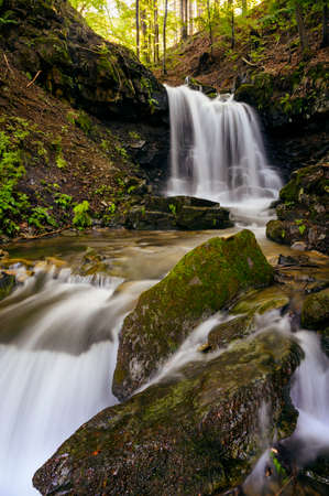 Larger waterfall on the river in the forest.
