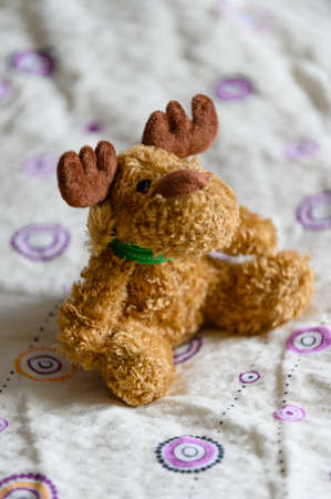 Plush figurine of a sitting moose.