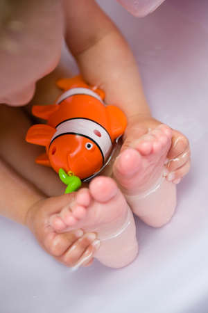 Plastic fish and baby feet in a tub of water.