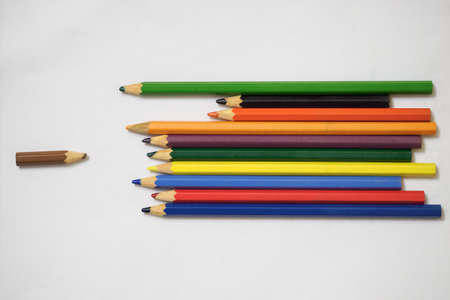 A small brown crayon against larger colored crayons.
