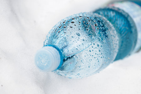 Water drops on a plastic bottle in the snow.