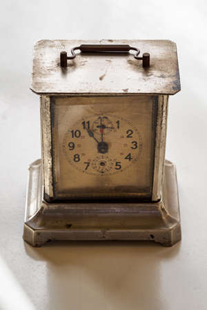 Old metal clock with a handle on the table.