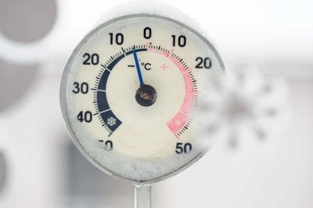 Detail of an outdoor hand thermometer with a freezing value behind the window.の写真素材