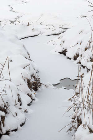 Frozen river with snow receding.の写真素材