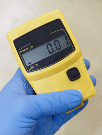 Dosimeter with a number on the display held in the hand with a blue glove.
