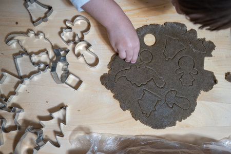 Gingerbread dough is cut out by a child's hand.