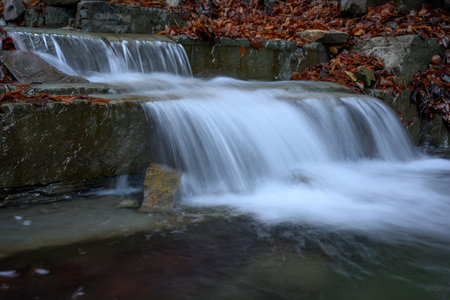 Waterfall in the forest in autumn, closeup of photo.
