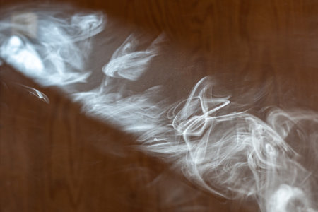 Cigarette smoke in a trickle of light.