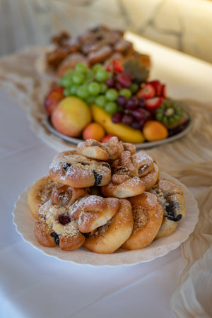 Various types of wedding pastries on a white plate with fruit in the background.の写真素材