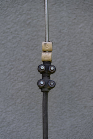 Labeled down conductor for a lightning protection system, captured in natural outdoor light, showing the identification tag and its integration with the building's grounding systemの写真素材