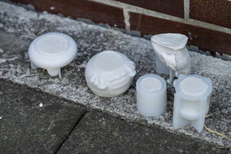Silicone molds filled with plaster outdoors on concrete near a tiled wall, captured in natural light, showing the contrast between soft casting material and hard surfaces.の写真素材
