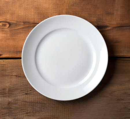 Empty white plate on wooden background. Top view. Copy space.の素材