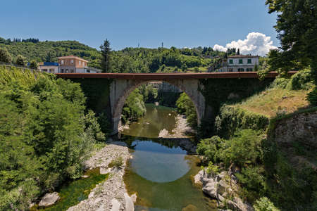 Bridge reflecting on the water of a river at Castelnuovo di Garfagnana at the Tuscany Region in Italyの写真素材