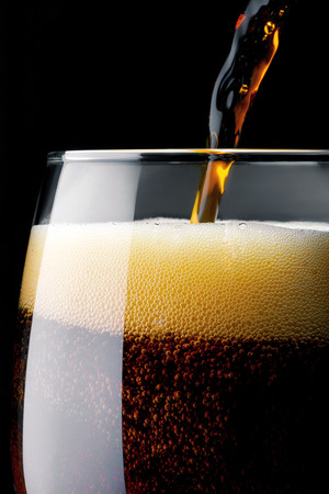 Beer into glass on a dark blackgroundの写真素材