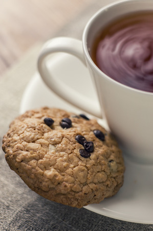 A tea and some chocolate chip cookies  on a brown wooden table.の写真素材