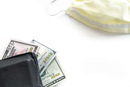 A twenty, fifty and hundred dollar bills fanned out and sticking out of a black leather wallet with...
