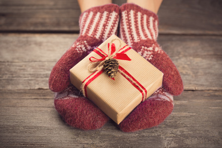 Hands in mittens holding gift boxの写真素材