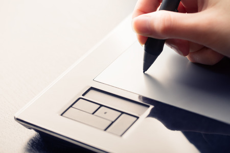 Hand of the designer with a pen on a tabletの写真素材