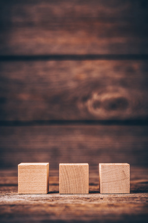 Three Wooden Cubes on Wood Background with Copyspaceの写真素材
