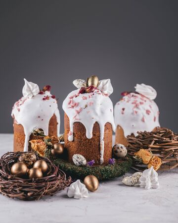 Easter cakes with nest and gold quail eggs on white table