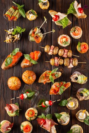 Set of different food snacks and appetizers on wooden background. Beautiful catering banquet buffet table.の写真素材