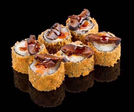 Hot Fried Uramaki Sushi roll with salmon, sauce and mushroom on top isolated on black background with reflectionの写真素材
